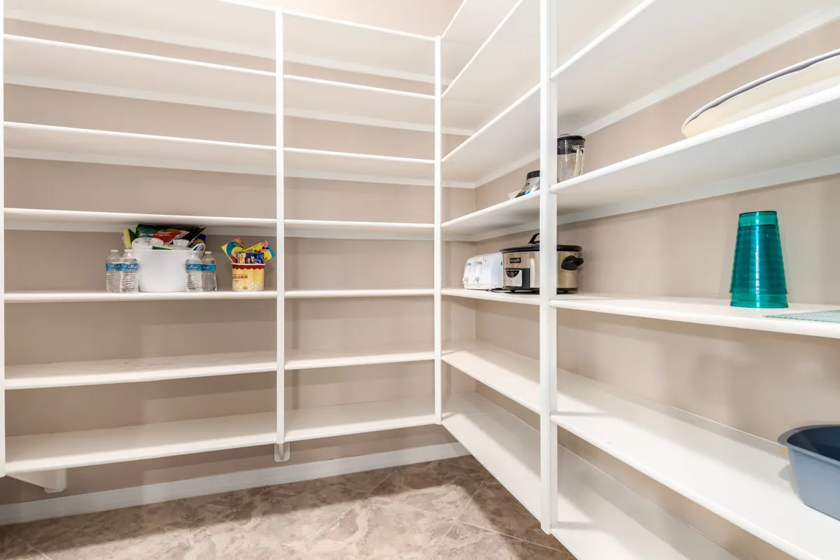 A practical, well-organized pantry lined with shelves, small appliances, and ample storage for kitchen essentials. The space feels efficient and ready to support any culinary activity.